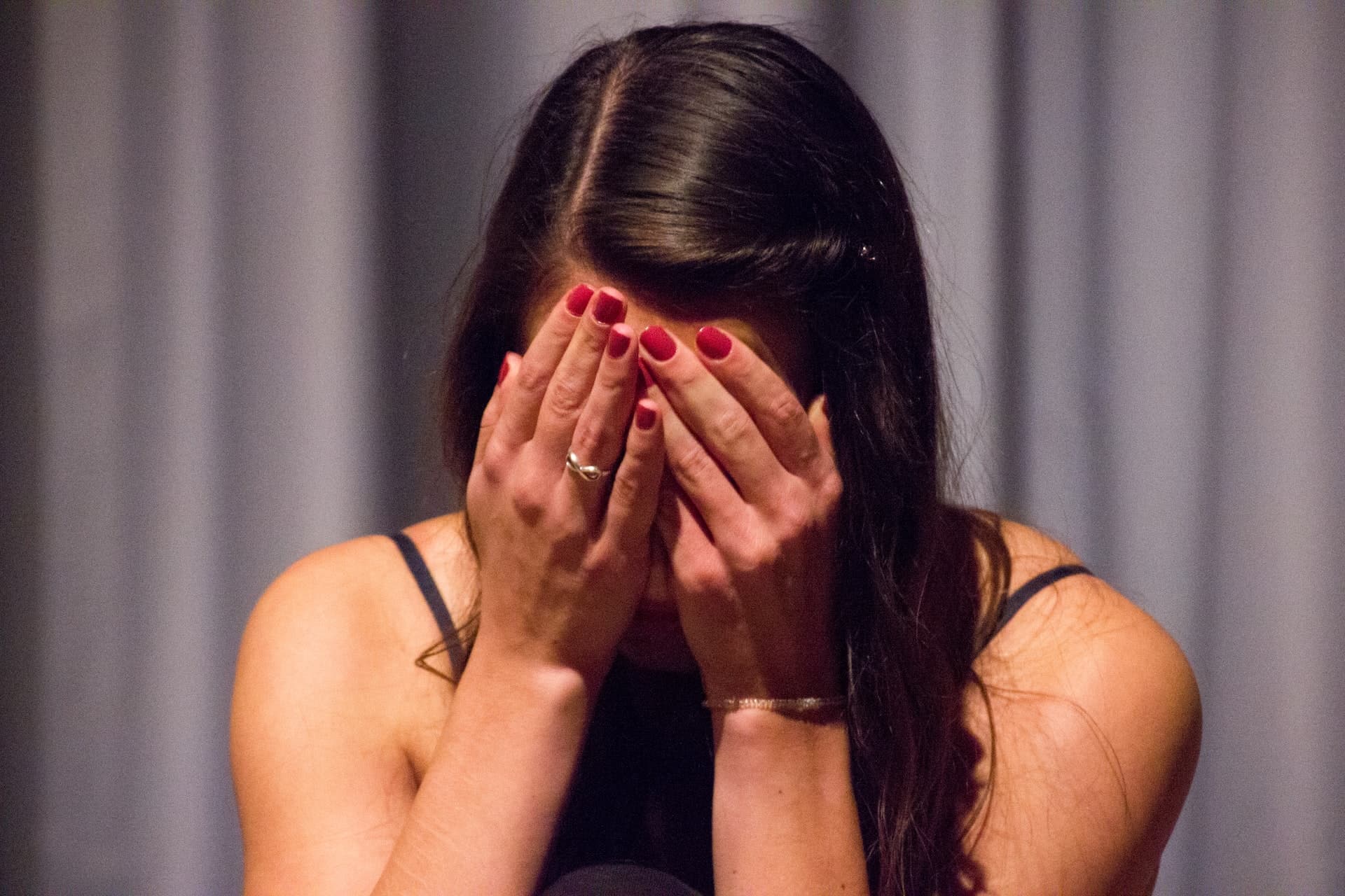 A picture of a woman holding both her hands in front of her face